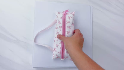 Beginner-friendly sewing pattern for a pink zippered pencil pouch with elastic, shown wrapped around school notebooks and a binder—perfect back-to-school supply case for pens, markers, and glue stick, aloha sewing company, bookmark, sewing tutorial video