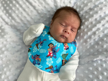 Newborn baby wearing a handmade traditional bib sewn from the printable PDF sewing pattern with matching boutique burp cloth.